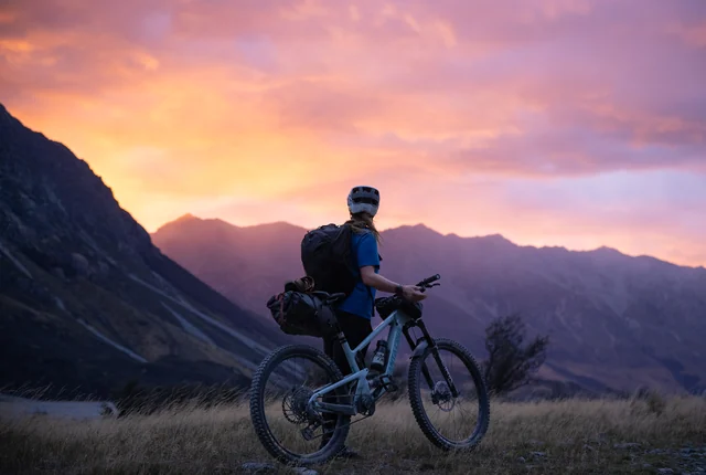 Annie Ford with her bike at sunset during a hut mission in Ahuriri Valley