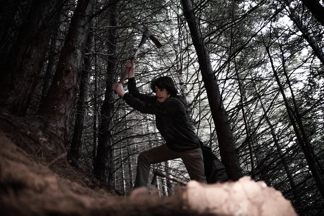 A trail builder swinging a pickaxe in the forest