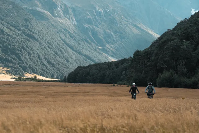 Two riders crossing a broad mountain valley