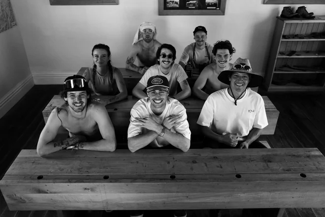 Eight friends smiling together, seated in three rows