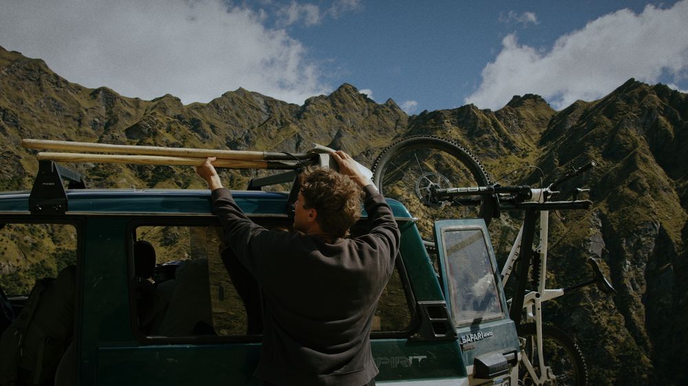 Loading bikes onto the roof of the truck with mountains behind