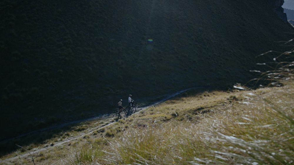 Two riders push along a high tussock ridge
