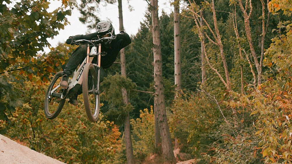 A rider airs a jump between autumn trees