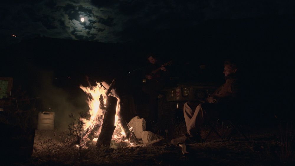 Friends around a campfire under the moon