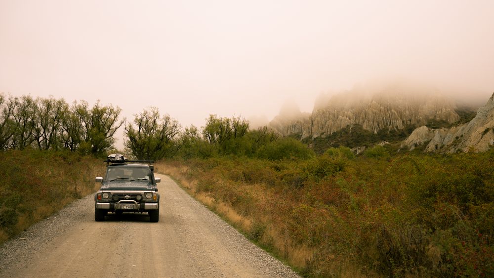 The truck on a gravel road in golden haze, cliffs behind