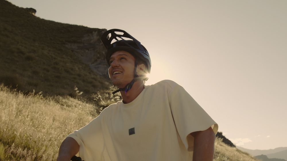 Henri in a helmet, backlit by the low sun on the hillside