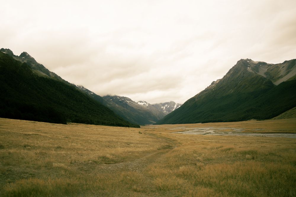 A wide tussock valley under heavy cloud, river winding through