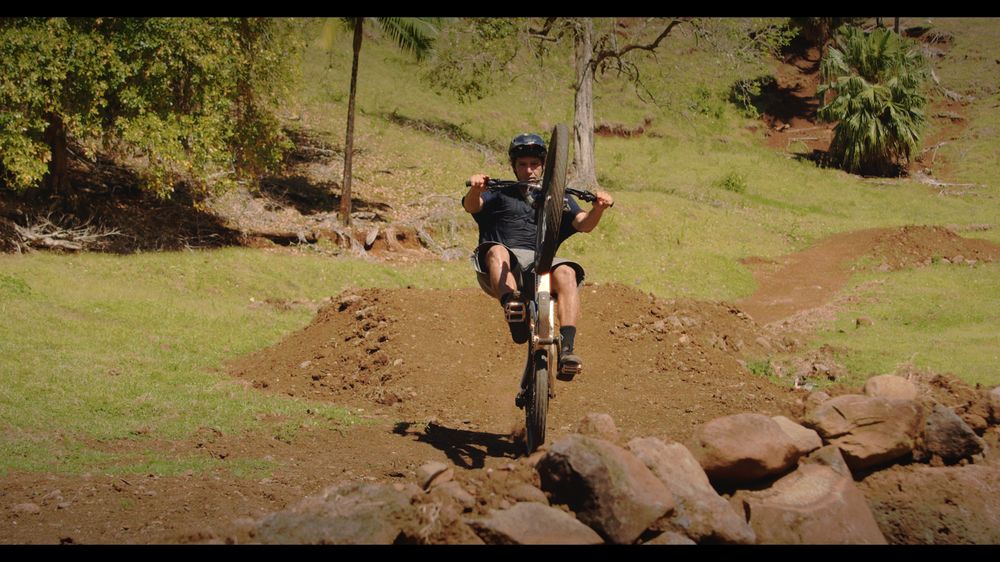 A rider lands a jump towards the camera over red earth